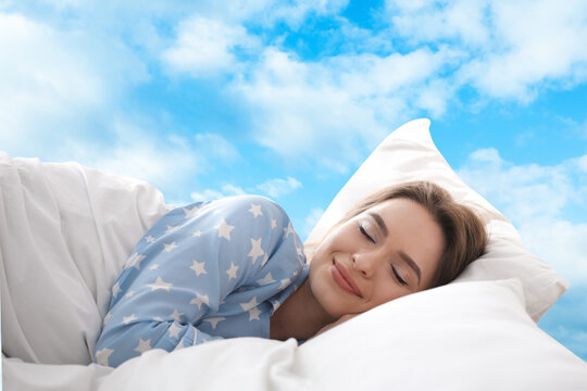 Young woman sleeping in bed. Blue sky on background