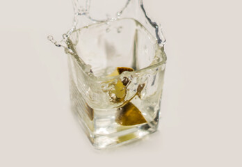 green lime fell into a glass with water on a white background