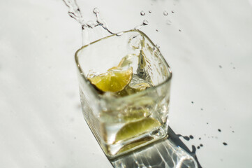 green lime fell into a glass with water on a white background