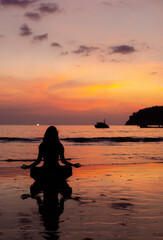 Fototapeta premium Evening yoga on the beach. Young girl practices yoga.