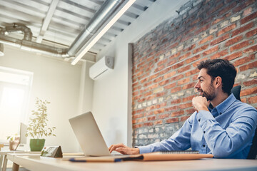 Happy businessman is using laptop at work