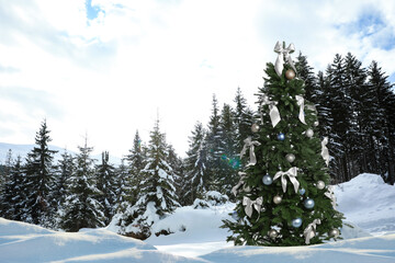 Beautiful decorated Christmas tree in snowy forest on winter day