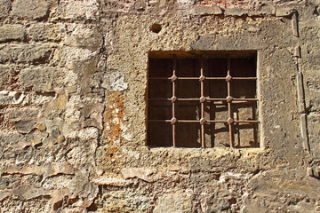 Closed window with rusty iron grate in ancient stone wall. Typical historic house in Istanbul 