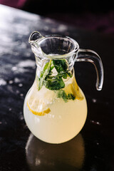 Refreshing summer drink lemonade, ice cubes and mint leaves. Vertical photo of a jug of lemon soda