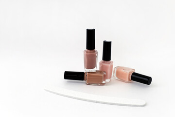 Natural beige and pink nail polish on a white background near a nail file