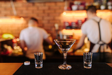 Dishes for cocktails and drinks in a nightclub on a bar against the backdrop of bartenders. Glass booze glasses with blurry background and bokeh