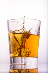 
whiskey splashes in a glass on a light background1