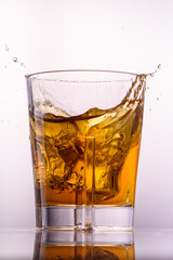 
whiskey splashes in a glass on a light background