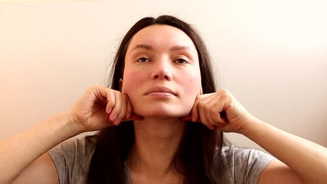 brunette girl does face massage, facebuilding, facelift, home care on the face, headshot