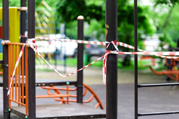 Fototapeta na wymiar The play park of amusement for young children is wrapped in red barrier tape. Prohibition of outdoor walks, prevention of the coronavirus influenza virus covid-19. childhood. selective focus
