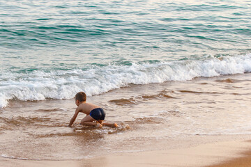 Little boy learn to swim by the sea. Active lifestyle. Weekends, holidays. Setting sun.