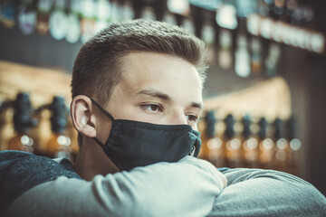 Pensive young guy in a black protective mask. A large portrait of a young man in a medical mask. Pandemic. Coronavirus. Covid 19. Summer 2020. Beer seller awaiting buyers.