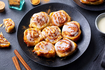 Cinnamon rolls, buns on black plate. Dark background. Close up.