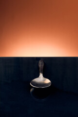 metallic spoon in black reflective table and orange background