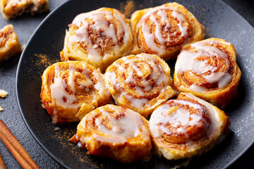 Cinnamon rolls, buns on black plate. Dark background. Close up.
