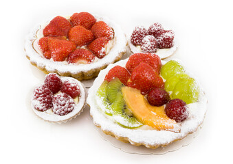 Small fruit cakes with various fruits and berries on white background