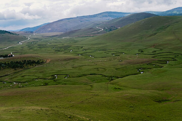 Meandering stream with mountains and clouds at The Persembe Plateau at Ordu, Turkey