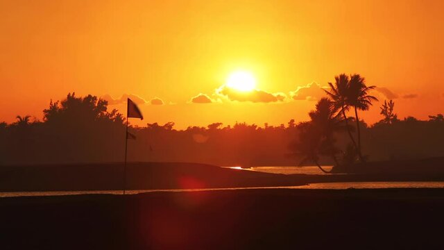Golf course in the tropical island, beautiful sunset with palm trees silhouettes video