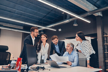 Young co-workers discussing new contract with gray-haired boss in office