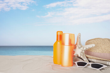 Set of sun protection products and stylish accessories on sandy beach. Space for text
