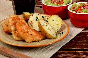 small chicken chops with boiled potatoes and green lettuce with olives and sunflower seeds