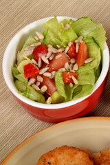 green lettuce with tomatoes and green olives next to fried potatoes and breaded cutlets