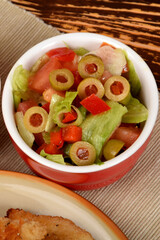 green lettuce with tomatoes and green olives next to fried potatoes and breaded cutlets