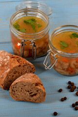homemade tripe soup in a jar with fresh green parsley next to bread