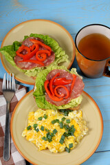 scrambled eggs with chives, a colorful sandwich and tea on an old blue table