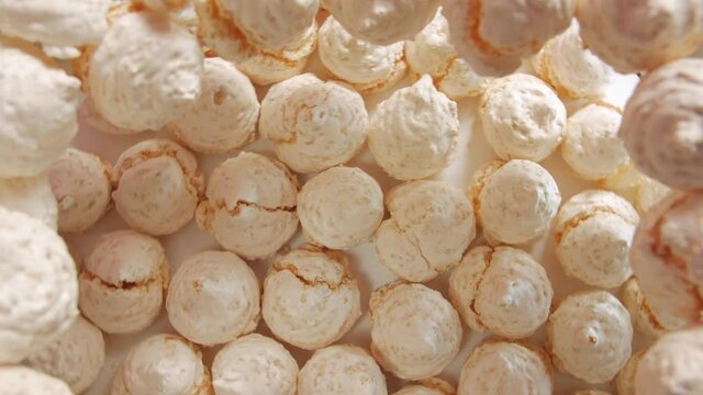 Sweet pastries meringues light pink peach colour clockwise fast rotation table top still life