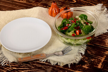 empty white plate next to the glass bowl with lettuce