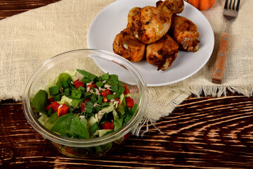 green lettuce with sunflower seeds and roasted chicken legs on a white plate