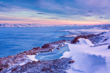 A frozen lake and the Barents Sea coast in winter at sunset. Teriberka, Murmansk Region, Kola Peninsula. Russia