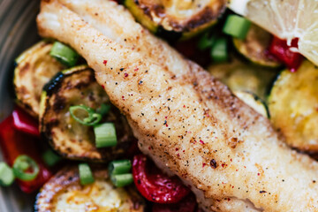 Plat de poisson filet de colin accompagné de légumes courgettes poivrons citron frais