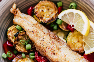 Plat de poisson filet de colin accompagné de légumes courgettes poivrons citron frais