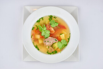 soup with meat, pepper, tomatoes, greens on a white background