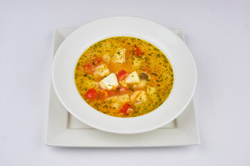 soup with potatoes, cheese, tomatoes and greens on a white background