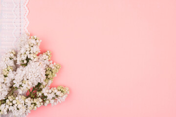 White flowers and lace on a pink background.