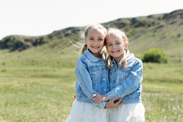 Portrait of two twin sisters who embrace in a meadow in nature