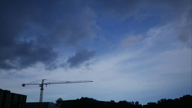 Time lapse of moving  cloud with blue sky. Silhouette crane, building and tree forest background at day time