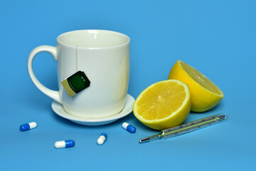 beautiful sliced lemons, a mug with tea and a thermometer on a blue background yellow