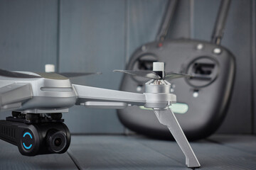 Close-up of quad-engine drone mounted camera and dual frequency radio control remote control in the background on gray wooden background