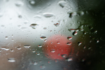 Raindrops on a windscreen glass with a blurred night city lights at the background.