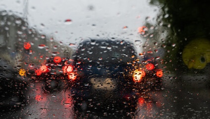 Raindrops on a windscreen glass with a blurred night city lights at the background.