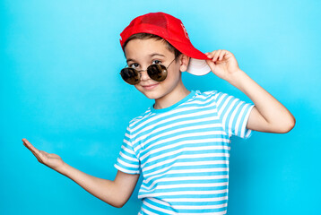 Crazy boy wearing a striped t-shirt and sunglasses with a baseball cap on his head over an isolated...