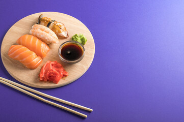 Delicious appetizing nigiri sushi set served on wooden plates with soy sauce and chopsticks. Purple...