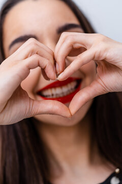 Beautiful woman making heart with fingers. Beautiful smile. Red lips.