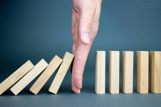 Businessman hand stopped wood blocks. Business risk management concept, businessman protects the fall of the wooden block to planning and strategy at risk for a business alternative and prevents. 