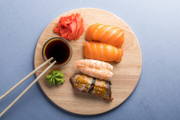 Delicious appetizing nigiri sushi set served on wooden plates with soy sauce and chopsticks. Gray background