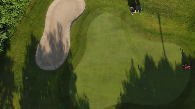 Gold course green maintenance from above. Lawn mower on green in Switzerland